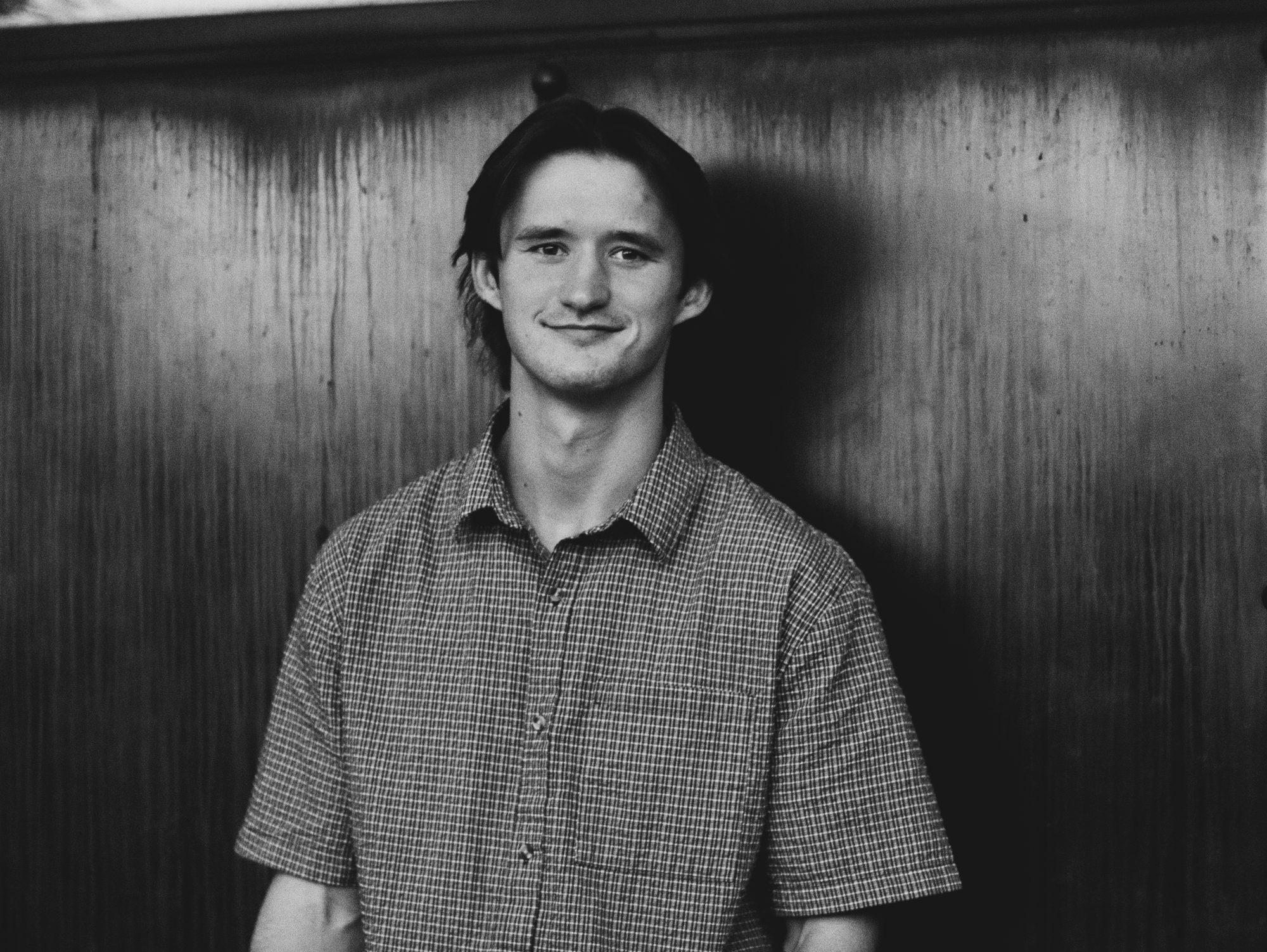 Boston smiling in front of a wood-panelled wall